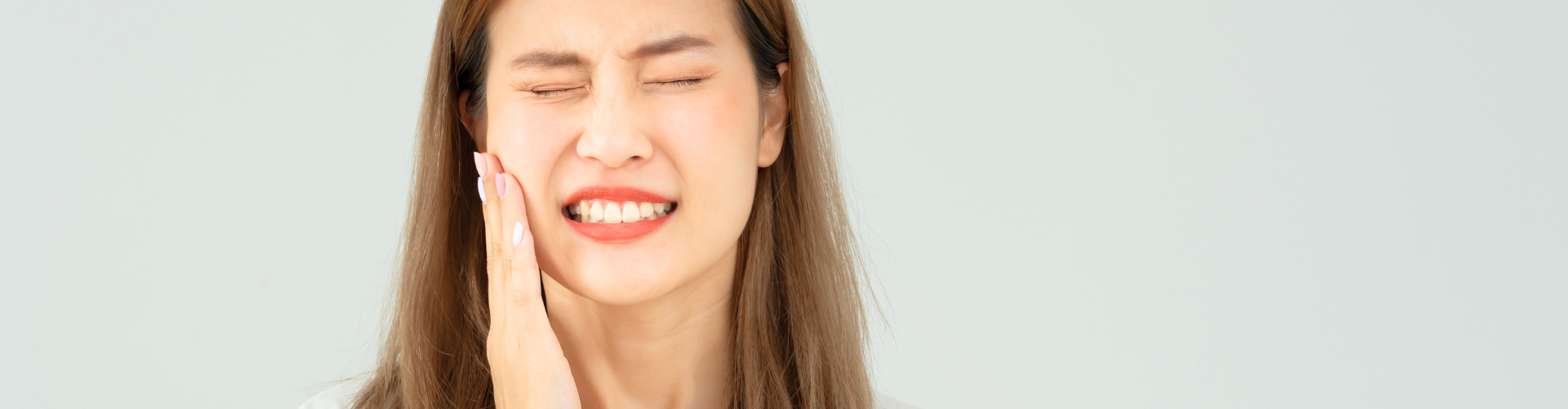Woman holding her cheek in pain.